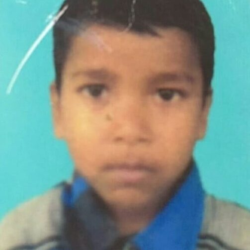 A young boy is standing in front of a blue background.