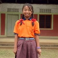 44 A girl in an orange shirt and plaid skirt.