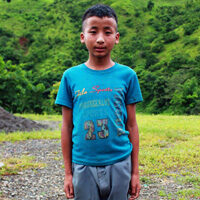 A young boy standing in front of some trees