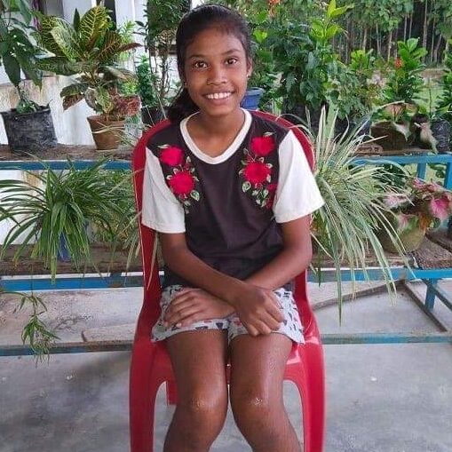 A girl sitting on top of a red chair.