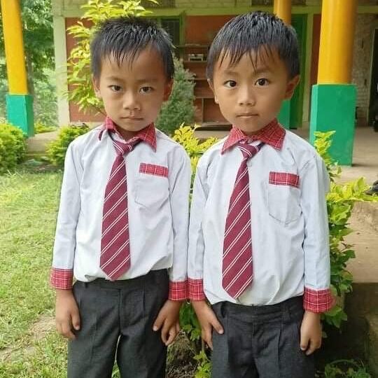 Two young boys in dress clothes standing next to each other.