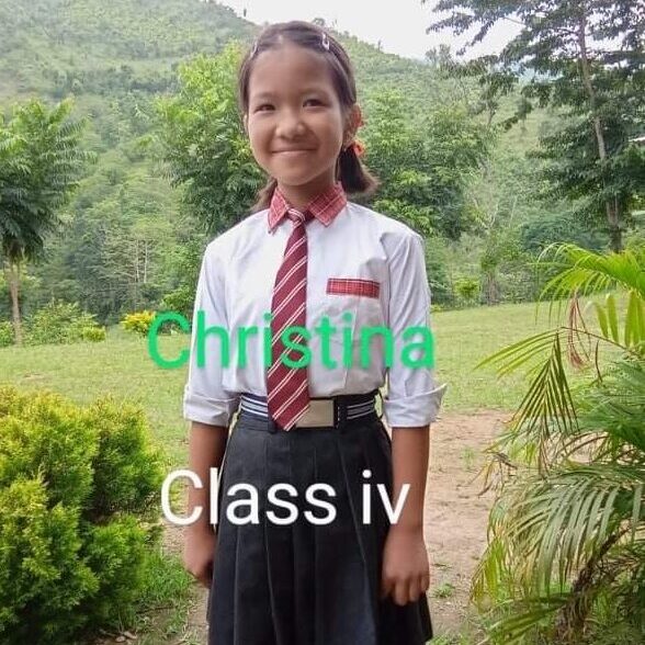 A girl in school uniform standing outside.