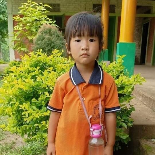 A young boy in an orange shirt and a pink cup