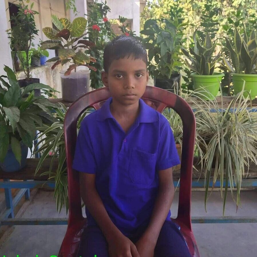 A boy sitting in a chair with plants behind him.