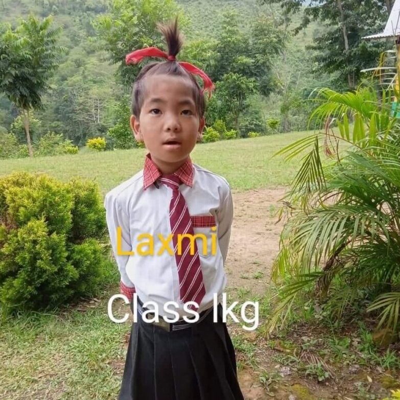 A young girl in school uniform standing outside.