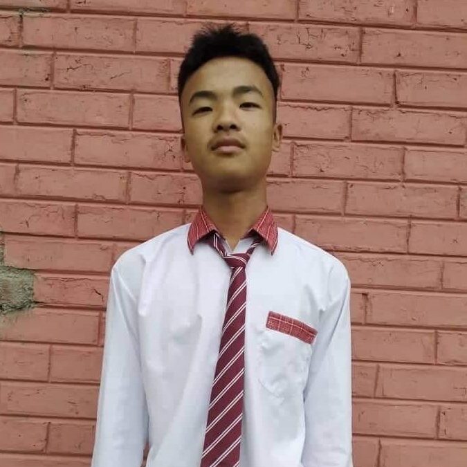 A young man wearing a tie standing in front of a brick wall.