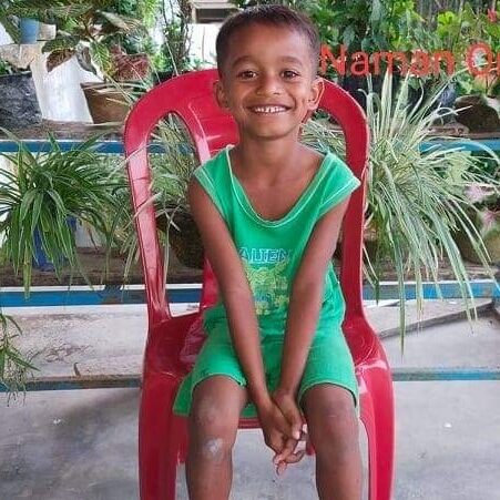 A young boy sitting on top of a red chair.