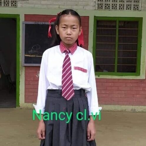A girl in school uniform standing outside of a building.