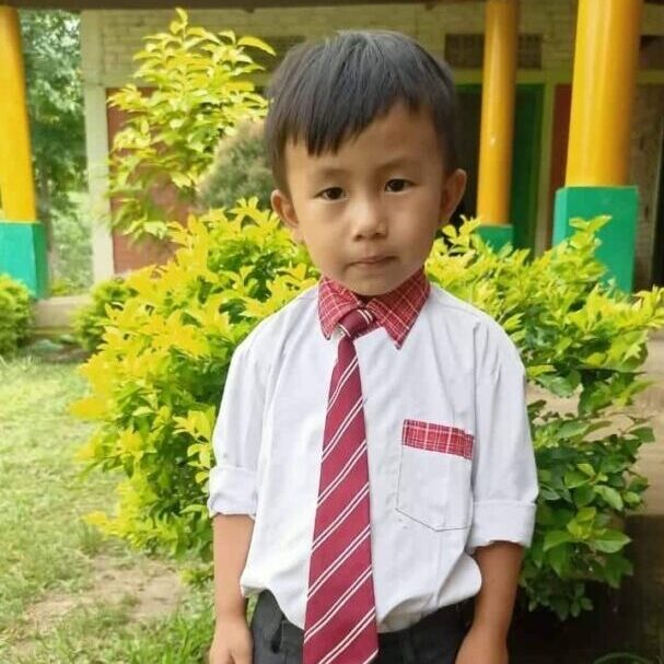 A young boy wearing a red tie and black pants.