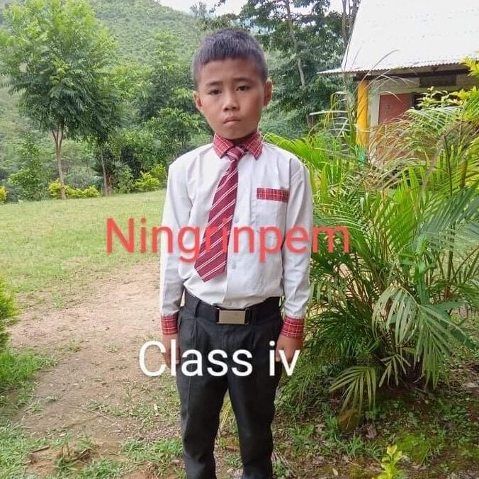 A young boy in a red tie standing outside.