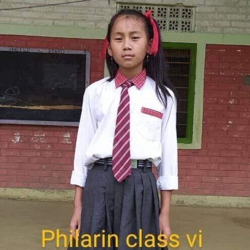 A girl in school uniform standing outside of a building.
