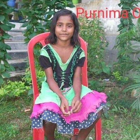 A girl sitting on top of a red chair.