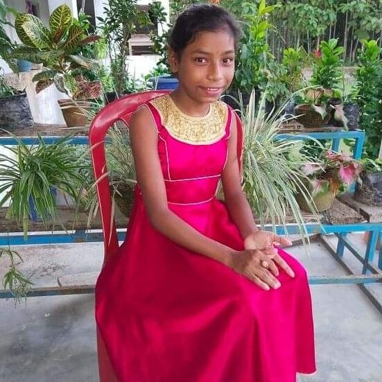 A girl in a red dress sitting on top of a bench.