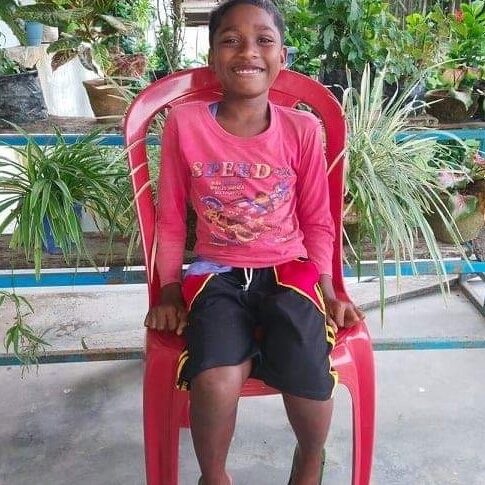 A young boy sitting in a red chair.