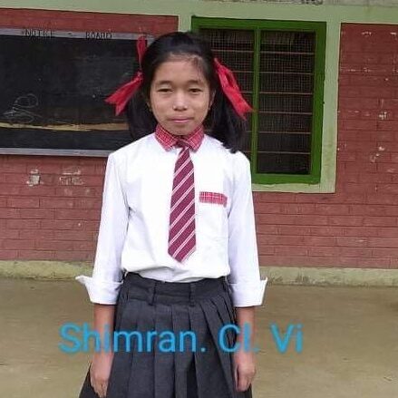 A girl in school uniform standing outside of a building.
