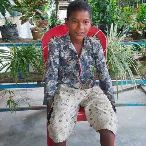 A young boy sitting in a red chair.