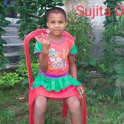 A girl sitting on top of a red chair.
