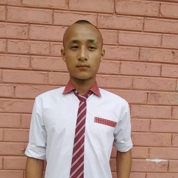 A man in a tie standing next to a brick wall.