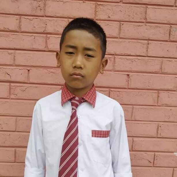 A young boy wearing a red tie and white shirt.