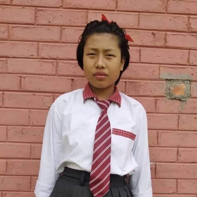 A young girl wearing a tie and pants.