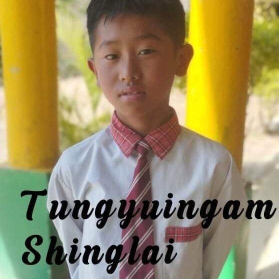 A young boy wearing a tie and standing in front of yellow pillars.