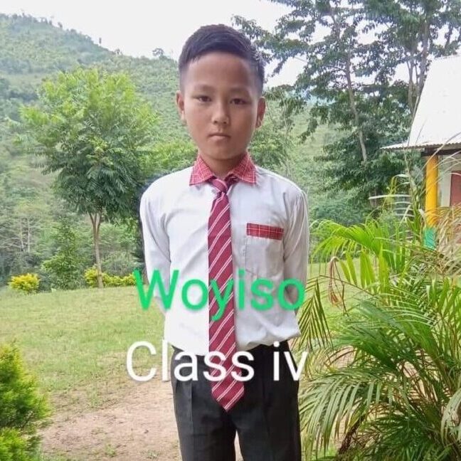 A young boy wearing a red tie and black pants.